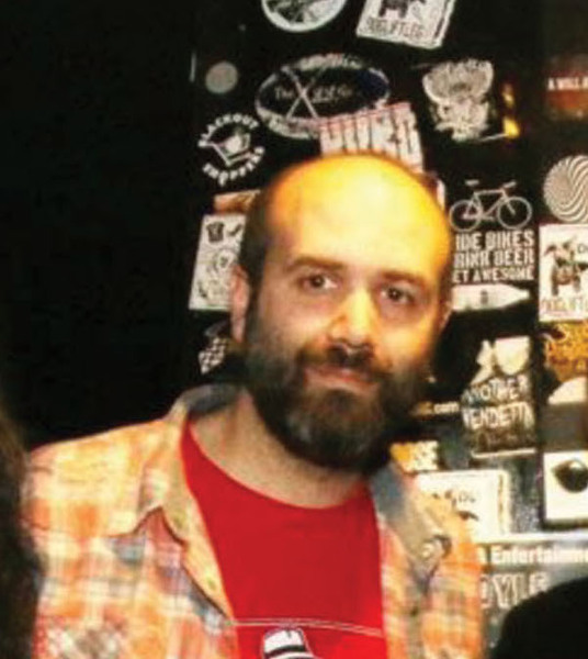 Josh Kantor infront of a wall of band stickers